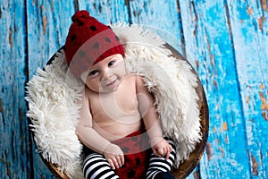 Little baby boy with knitted hat in a basket, happily smiling