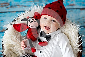 Little baby boy with knitted ladybug hat and pants in a basket