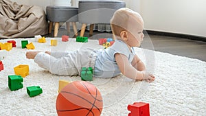 Little baby boy lying on floor in living room full of toys