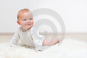 Little baby boy lying on the floor and smiling on white background, baby crawling on floor