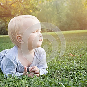 Little baby boy lying on the green grass outdoor