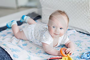 Little baby boy 3 months old lies on his stomach on the sofa in a bright room, the child smiles