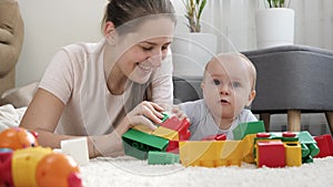 Little baby boy with mother playing toys on carpet in living room. Concept of children development, education and