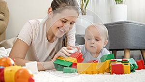 Little baby boy with mother playing toys on carpet in living room. Concept of children development, education and