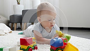 Little baby boy playing with colorful toy cars on carpet in living room. Concept of children development, education and