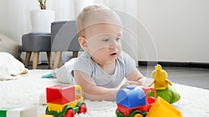 Little baby boy playing with colorful toy cars on carpet in living room. Concept of children development, education and