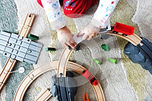 Little baby boy playing with colorful wooden train on the carpet