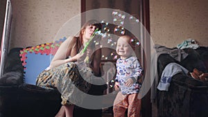 Malý dieťa chlapec jeho matka ktorý fúkania mydlo bubliny zatiaľ čo dieťa šťastne nákazlivý je vnútri v 