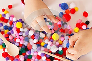 Little baby boy playing with small pompoms. Development of kids motor skills, coordination and logical thinking