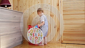 A little baby boy plays with his toys in sunny room