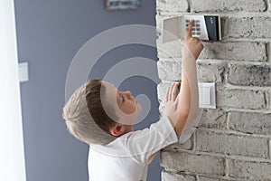 Little baby boy pushes a buttons on the alarm keypad