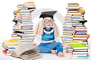 Little Baby Boy Reading Books. Happy Smiling Child in Graduation Cap Studying. Funny Kid in Glasses sitting next to Stack of Books