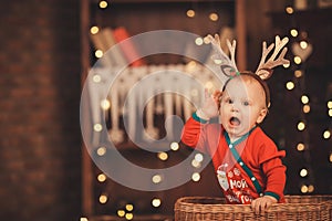 Little baby boy in reindeer antlers sitting in a wicker basket