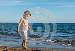 Little baby boy running along the coast of the sea. Positive human emotions, feelings,