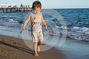Little baby boy running along the coast of the sea. Positive human emotions, feelings,