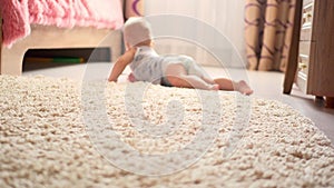 Little baby boy of seven months, crawling on the floor at children room. Kid crawling on the carpet, back view.