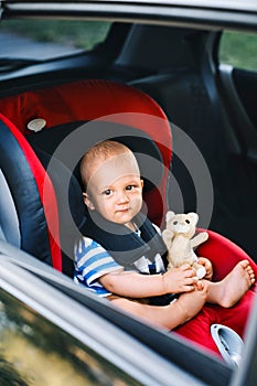 Little baby boy sitting in the car seat in the car.