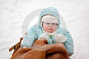 Little baby boy in sledge on winter snow day