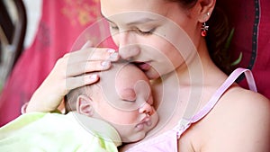 Little baby boy sleeping on mom`s chest outdoor. mother hugging sleeping baby in her arms and kissing the kid gently