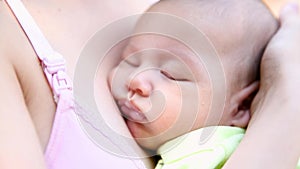 Little baby boy sleeping on mom`s chest outdoor. mother hugging sleeping baby in her arms and kissing the kid gently