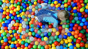 A little baby boy sliding on slide in a ball pool.