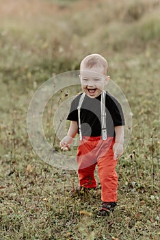 Little baby boy smiling standing on grass in summer field
