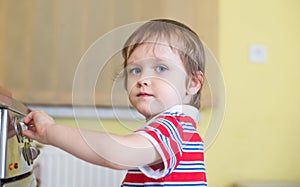 Little baby boy is touching cooker - danger in home