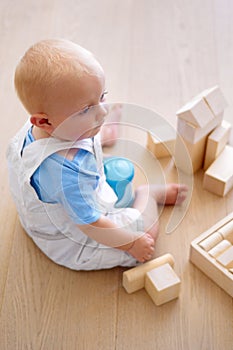 Little baby boy, toys and wooden blocks on floor for playtime, learning or childhood development at home. Cute, adorable