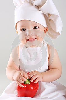 Little baby in a cap chef with Pepper