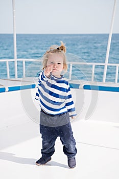 Little baby captain on boat on summer cruise, nautical fashion