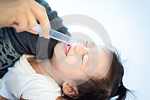 little baby child has been cleaning snot form running nose by her mother with saline in syringe