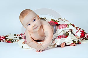 Little baby covered with a blanket on bright gray background