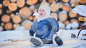 A little baby is crying sitting in the snow.