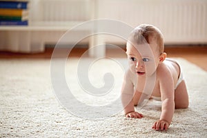 Little baby in diaper crawling on floor at home