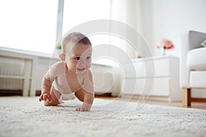 Little baby in diaper crawling on floor at home