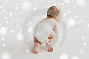 Little baby in diaper crawling on white floor
