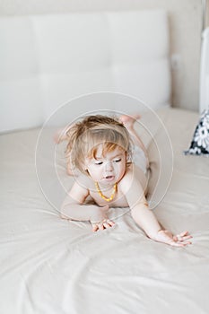 little baby in a diaper lies on the bed and laughs