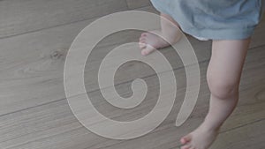 Little baby doing first steps tiny bare feet meeting floor. With first steps child embarks on journey of discovery