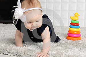 Little baby in dress creeps on grey soft carpet photo
