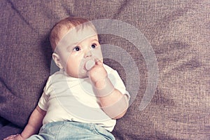 A little baby with a dummy is crying while sitting on the bed. Disputes and quarrels mothers with small child