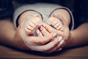 Little baby feet in mother's hands. Child care, feeling safe, protect.