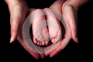 Little baby feet in mother`s hands