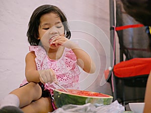 A little baby girl, 3 years old, learning to have a fresh watermelon by herself - encourage your child to eat fruits