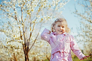 Little baby girl 3 years, that runs between flowering trees outd