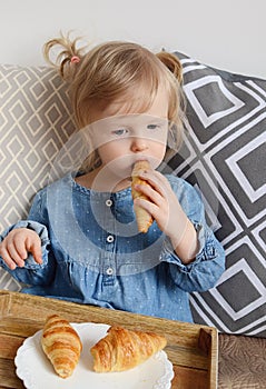 Little baby girl age of 1,11 years eating croissants