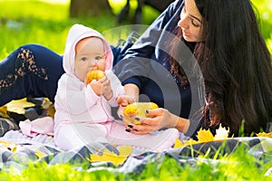 Little baby girl biting a ripe golden apple.