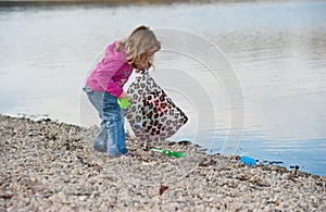 Little baby girl cleaning the beach