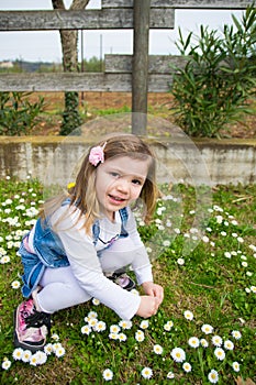 Little baby girl collects daisies in a playground