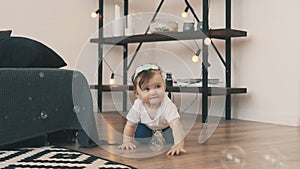 Little baby girl crawling on the floor in the room with young mother