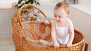 a little baby girl is crying and trying to get out of the crib cradle, a child with tears calling mom in a wicker crib